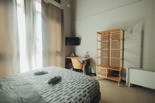 Camera moderna dell'Oltre Exclusive a Palermo con letto queen, guardaroba in legno, scrivania con TV e vista sulla città