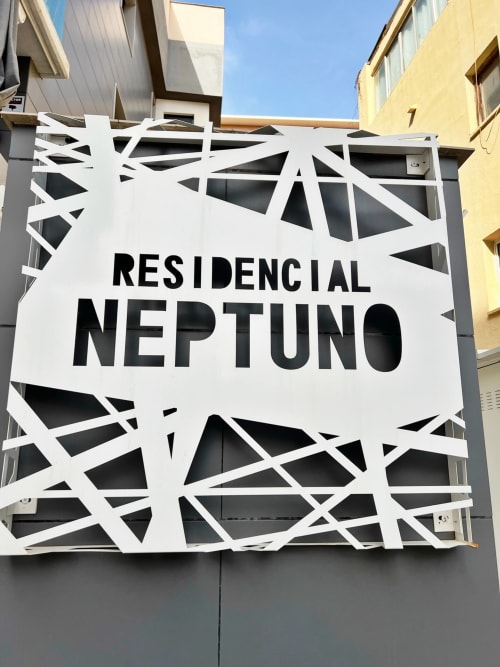 Letrero Residencial Neptuno con diseño de patrón geométrico blanco en fachada gris en Fuengirola