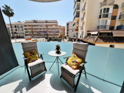 Terraza moderna en la azotea de Fuengirola con tumbonas, mesa blanca y vistas de la ciudad, amenidad de lujo