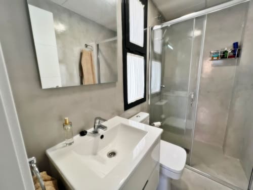 Baño moderno en lujoso apartamento de Fuengirola con lavamanos blanco, espejo, ducha y inodoro