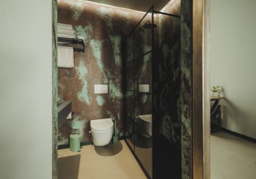 Bagno moderno nella suite Oltre Exclusive dell'hotel Palermo, con pareti in metallo ossidato industriale, wc bianco e cornice nera