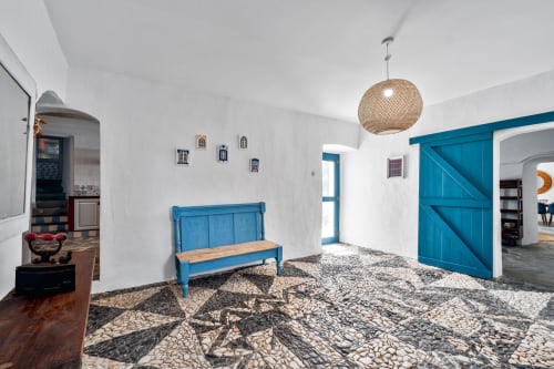 Entrada minimalista e luminosa da villa Casa do Loureiro em Alandroal com paredes brancas, detalhes azuis, luminária de palha trançada e