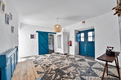 Interior branco luminoso com portas azuis e piso com padrões tradicionais na villa Casa do Loureiro, Alandroal