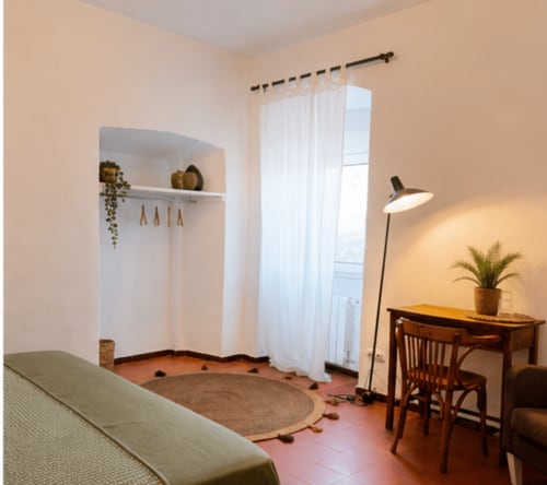 Habitació acollidora a Mas Ribas de Palamós amb espai de treball, llum natural i cortines amb vista al jardí