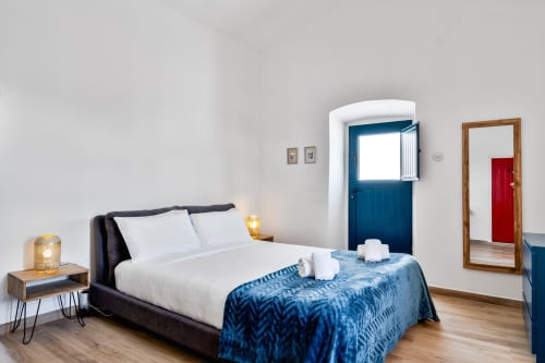 Quarto moderno da villa Casa do Loureiro em Alandroal com toques azuis, roupa de cama branca e piso em madeira