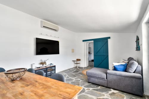 Sala de estar moderna na villa Casa do Loureiro em Hospedar Alandroal com sofá cinza, mesa de madeira, TV tela plana e tons de azul-petróleo