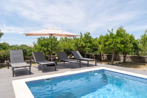 Deck da piscina da villa Casa do Loureiro em Alandroal com espreguiçadeiras, guarda-sol e vista para o jardim