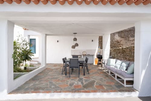Pátio coberto da villa Casa do Loureiro em Alandroal com mesa de jantar, lareira em pedra, cozinha e área de estar