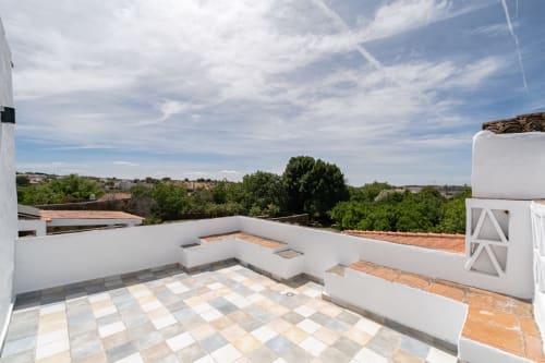 Terraço na cobertura da vila Casa do Loureiro em Alandroal com pátio azulejar, paredes brancas, vistas rurais e céu azul