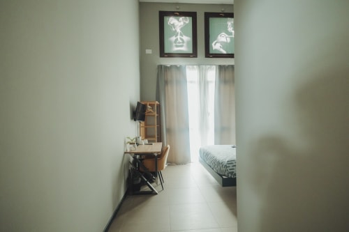 Elegante camera doppia deluxe presso Oltre Exclusive a Palermo con scrivania, letto e vista sulla corte interna attraverso ampie finestre
