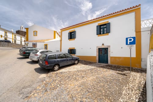 Área de estacionamento da villa Casa do Loureiro com fachada amarela e branca em Alandroal, Portugal