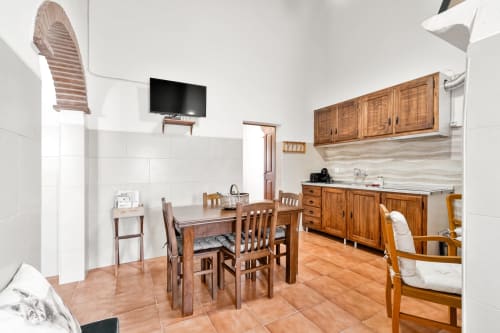 Cozinha e sala de jantar da Casa do Ti Filipe com móveis de madeira, azulejos brancos e piso em terracota no apartamento Airbnb