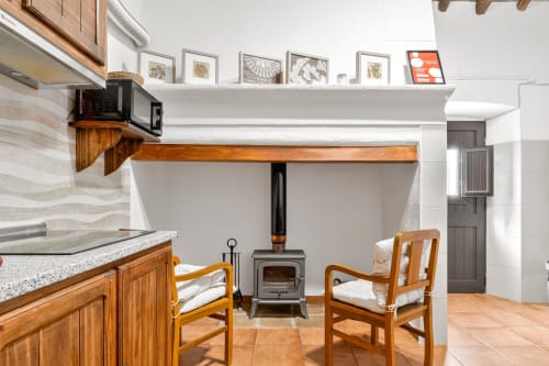 Interieur do apartamento Casa do Ti Filipe com cozinha de madeira, área de refeições, fogão com lareira e mobiliário rústico em Portugal.