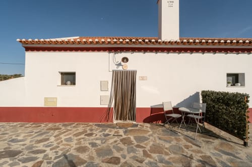 Exterior da Casa do Ti Filipe com terraço, paredes vermelhas e brancas, área de refeições ao ar livre e vistas para a montanha em MontesJuntos