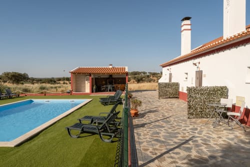Piscina e pátio da Casa do Ti Filipe com espreguiçadeiras, casarões de telhado vermelho e vistas da campanha alentejana, Portugal