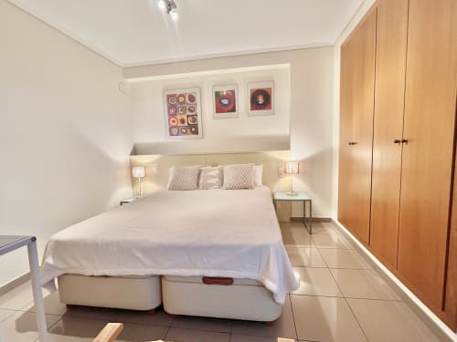 Dormitorio moderno en apartamento con vistas al mar en Valencia, cama queen, armarios de madera y cuadros enmarcados
