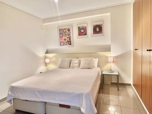 Dormitorio moderno en apartamento con vistas al mar en Valencia, cama doble, lámparas de noche y obra de arte abstracto