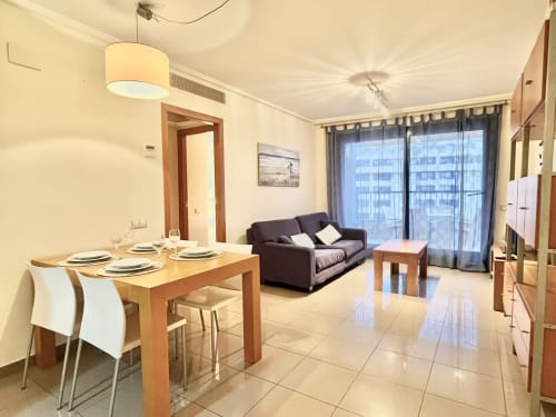 Apartamento moderno en Valencia con vistas al mar, mesa de comedor, sofá oscuro y sala de estar amueblada