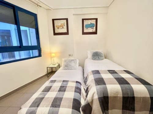 Habitación doble con vistas al mar en apartamento de Valencia en Pataconablue Rentals, con ropa de cama a cuadros y comodidades modernas