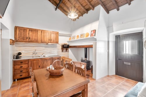 Cozinha e sala de jantar rústica com vigas, armários e mesa de madeira no apartamento Casa da Ti Inácia
