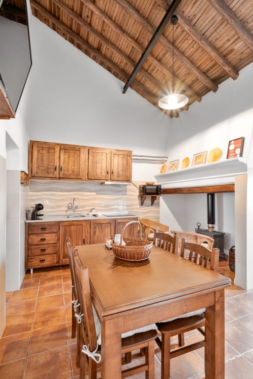 Cozinha e sala de jantar rústica com vigas de madeira, móveis planejados e mesa em Casa da Ti Inácia