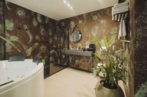 Bagno lussuoso nella Oltre Exclusive Deluxe Suite di Palermo, con vasca idromassaggio, doccia a pioggia, carta da parati ricercata e piante in vaso