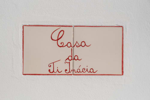 Placa de parede Casa da Ti Inácia em caligrafia vermelha sobre azulejo branco, decoração de boas-vindas de hospedaria portuguesa