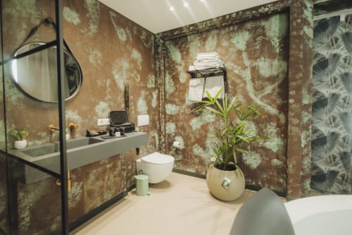 Lussuoso bagno presso Oltre Exclusive a Palermo con pareti in rame invecchiato, vanità moderna, wc bianco, pianta in vaso e