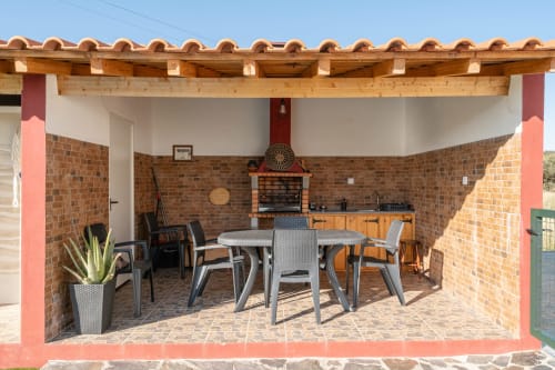 Área de refeições externa coberta com lareira de tijolos na Casa da Ti Inácia, apartamento Airbnb em Montes Juntos