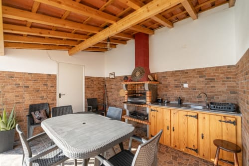 Cozinha e sala de jantar modernas com paredes de tijolos, vigas de madeira, lareira e mesa na Casa da Ti Inácia