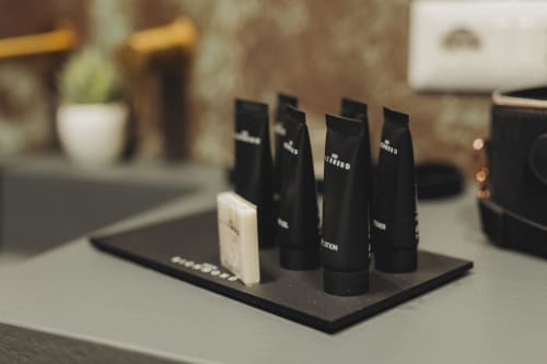 Articoli da toilette omaggio esposti su vassoio nero nel bagno della suite deluxe Oltre Exclusive, hotel Palermo