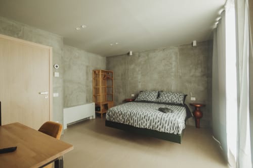 Ampia suite deluxe presso Oltre Exclusive a Palermo con letto matrimoniale, arredi in legno, pareti in cemento e vista sulla corte