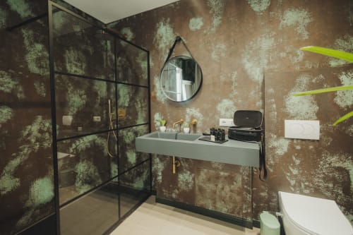 Lussuoso bagno dell'hotel Oltre Exclusive di Palermo con pareti dal patina verde rustico, lavabo sospeso e doccia con cornice nera
