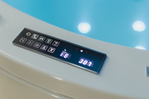 Pannello di controllo digitale con pulsanti funzione e display temperatura sul bordo della vasca bianca all'hotel Oltre Exclusive di Palermo