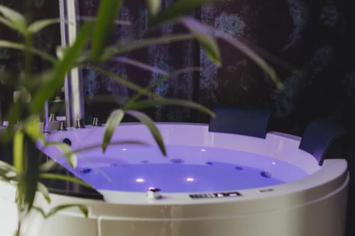 Vasca idromassaggio moderna con illuminazione viola e piante in vaso presso Oltre Exclusive a Palermo