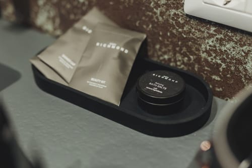 Set di amenities lussuosi neri presso l'hotel Oltre Exclusive di Palermo, con sali da bagno e kit bellezza sul piano del lavabo