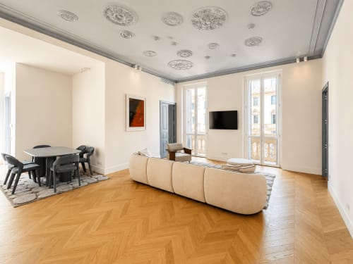 Suite Moderna Ingrid presso SEVEN SUITES SANREMO con divano beige curvo, zona pranzo, pavimenti in legno e vista città dal balcone