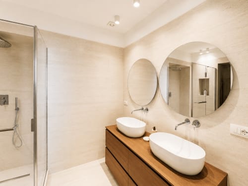 Bagno moderno della Suite Ingrid presso Seven Suites Sanremo con doppi lavabi bianchi, mobile in legno e specchi circolari