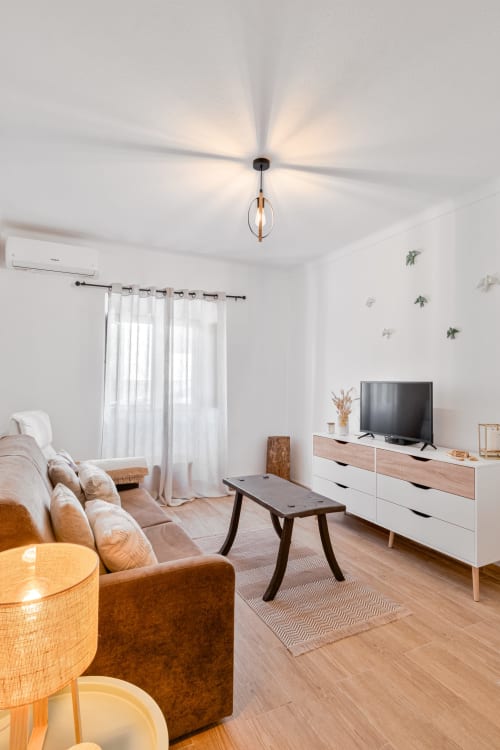 Sala moderna da Casa da Ritinha com sofá bege, móveis de madeira, TV e ventilador de teto