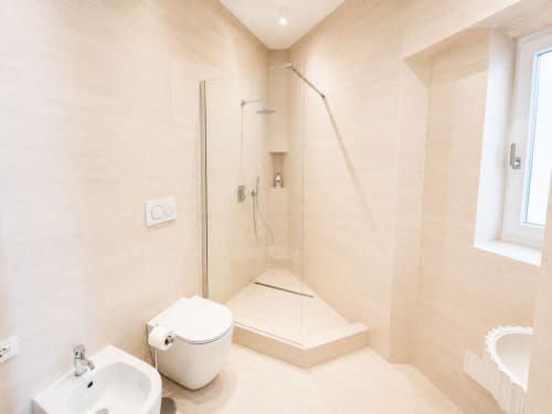 Bagno moderno della Suite Ingrid SEVEN SUITES SANREMO con doccia a pioggia, wc, bidet e finiture in piastrelle color crema