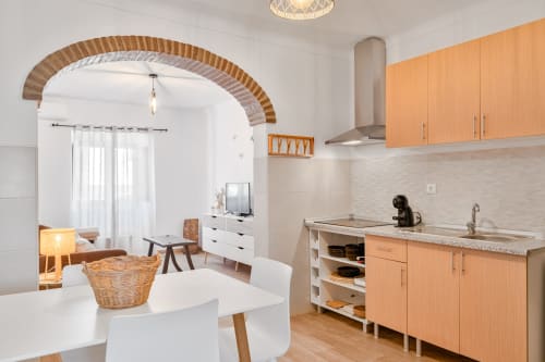 Cozinha e sala de jantar modernas no apartamento Casa da Ritinha com móveis de madeira, mesa de jantar branca e arco de tijolos