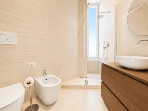 Bagno moderno della Suite Ingrid presso Seven Suites Sanremo con sanitari bianchi, mobile in legno, doccia a filo pavimento e piastrelle in marmo