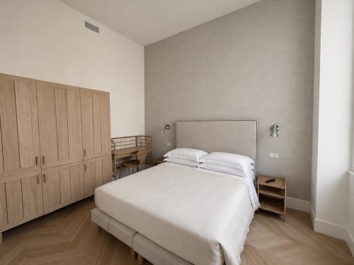 Camera moderna della Suite Ingrid a Seven Suites Sanremo con letto queen, armadio in legno e vista sulla città