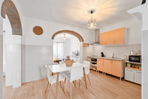 Cozinha e sala de jantar modernas no apartamento Casa da Ritinha com móveis em madeira, mesa branca e detalhes em arco de tijolos
