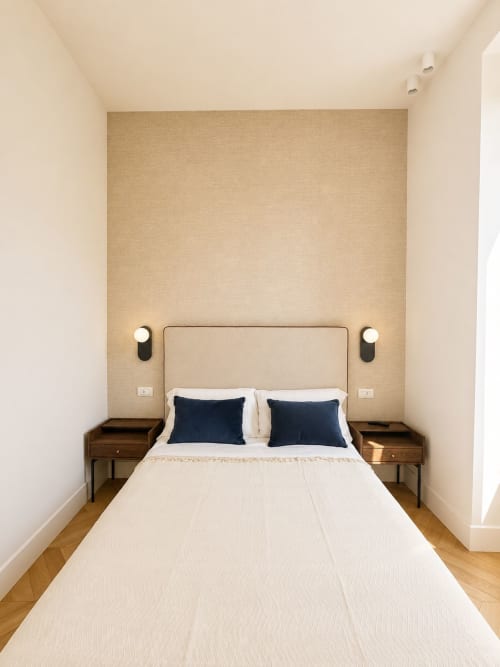 Camera moderna SEVEN SUITES SANREMO Suite Ingrid con letto color crema, cuscini blu navy, comodini in legno e applique da parete