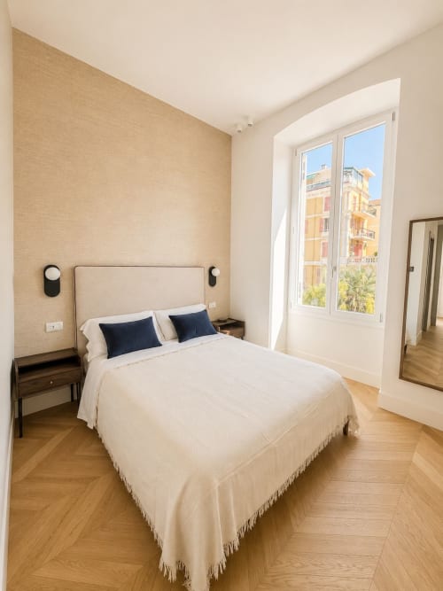 Camera moderna alle SEVEN SUITES SANREMO con vista sulla città, biancheria crema, pavimenti in legno e balcone con vista su Sanremo