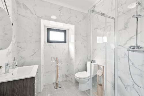 Banheiro moderno em mármore do apartamento Casa da Ritinha com chuveiro walk-in, pia branca e sanitário