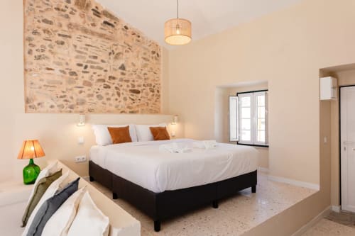 Modern bedroom with stone accent wall, queen bed, and terrace at FC Housing Company, Abrantes