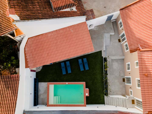 Vista aérea do apartamento da FC Housing Company em Abrantes com piscina turquesa, terraço e telhado de telha vermelha cercado de verde