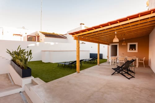 Terraço espaçoso no FC Housing em Abrantes com zona de estar, relva artificial, pérgula de madeira e apartamento de parede laranja